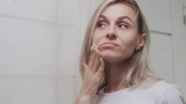 Gros plan de fille frustrée regarde son visage dans le miroir de la salle de bain — Photo