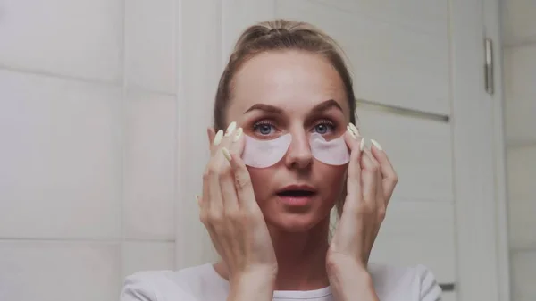 Close up of Woman put collagen pads under her eyes and look at the camera — Stok Foto