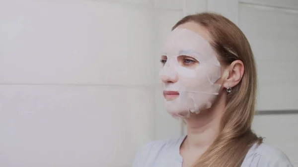 Zbliżenie na dorosłą kobietę nakładającą maskę na twarz i patrzącą w kamerę — Zdjęcie stockowe