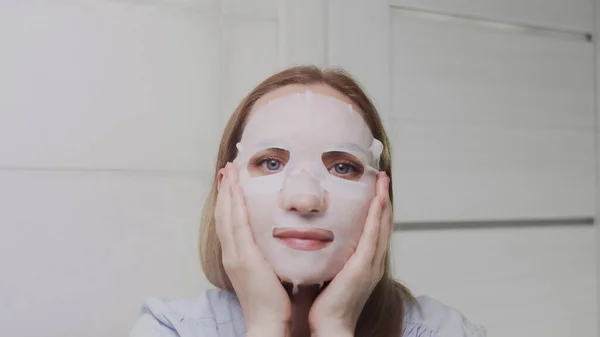 Крупный план взрослой женщины, надевающей маску на лицо и смотрящей в камеру — стоковое фото