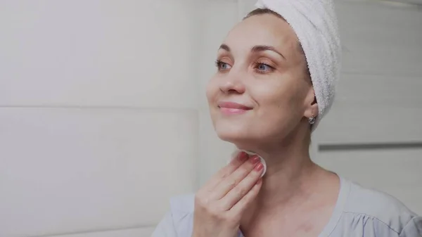 Adult woman with a towel on her head applying lotion and looking in mirror enjoy natural beauty and healthy — Stock Photo, Image