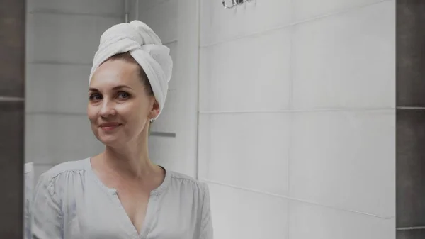 Wanita kaukasia dengan handuk di kepalanya di depan cermin di kamar mandi. Cucian wajah, perawatan kulit, kesehatan — Stok Foto