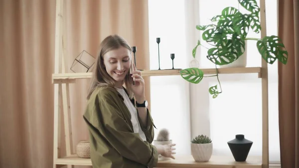 Attractive woman talks on the phone and check her cactus — Stock Photo, Image