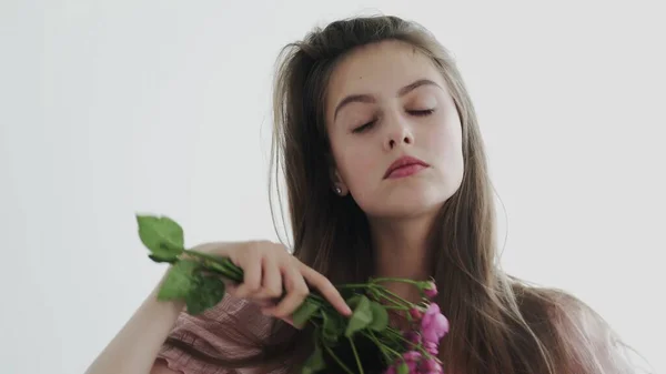 Atractiva hermosa modelo de mujer joven con flores mirando y posando en la cámara — Foto de Stock