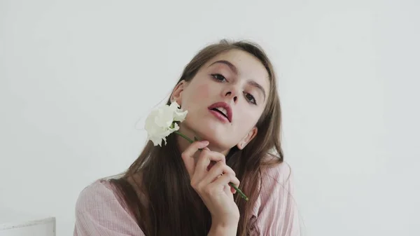 Atractiva hermosa modelo de mujer joven con flores mirando y posando en la cámara — Foto de Stock