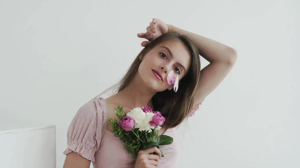 Atractiva hermosa modelo de mujer joven con flores mirando y posando en la cámara — Foto de Stock