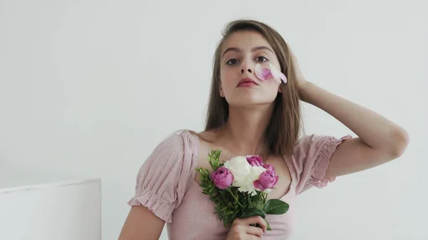 Jovem modelo profissional com flores olhando e posando para a câmera — Fotografia de Stock