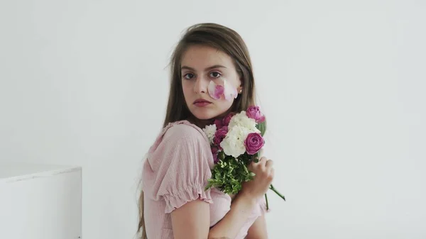 Çiçeklerle kameraya bakıp poz veren profesyonel bir kadın model. — Stok fotoğraf