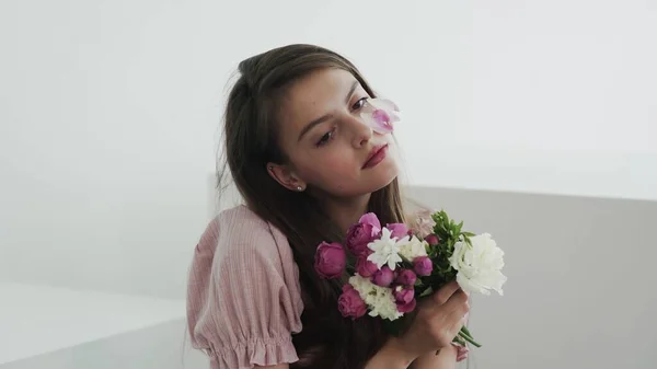 Професійна модель молодої жінки з квітами дивиться і позує на камеру — стокове фото