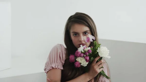 Професійна модель молодої жінки з квітами дивиться і позує на камеру — стокове фото