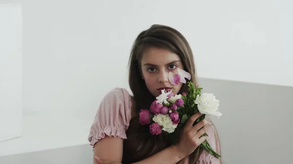 Jovem modelo profissional com flores olhando e posando para a câmera — Fotografia de Stock