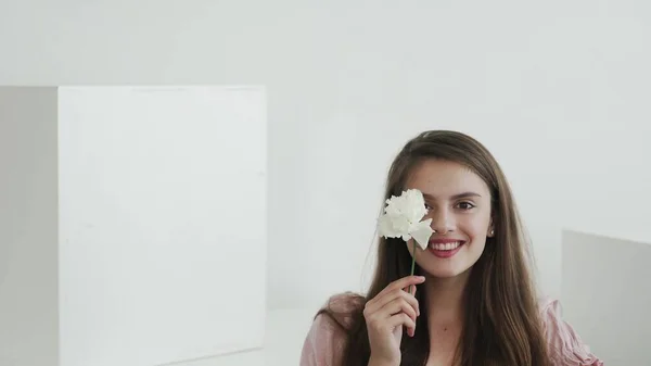 Atractiva hermosa modelo de mujer joven con flores mirando y posando en la cámara —  Fotos de Stock