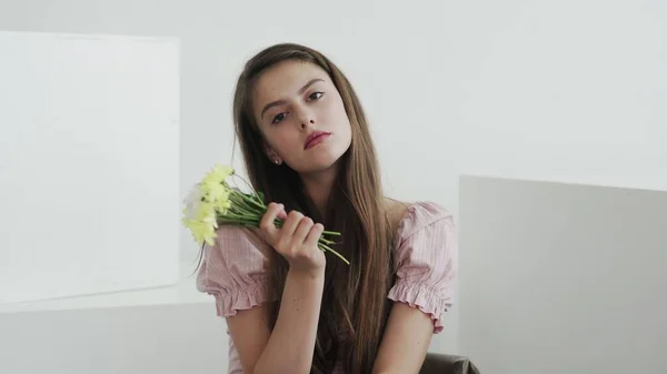 Çekici, güzel, genç bir kadın model. Çiçeklere bakıyor ve kameraya poz veriyor. — Stok fotoğraf