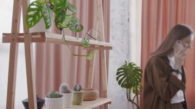 Kadın çiçekçi telefonda konuşuyor ve çiçekleri suluyor.