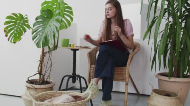 Güzel genç bir kadın sandalyeye oturur ve stüdyosunda bir resim çizer..