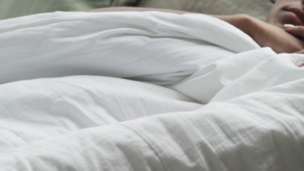 Junge Afroamerikanerin wacht einfach auf und sonnt sich im Bett. lächelnde attraktive Frau auf Bettlaken liegend und lächelnd — Stockvideo