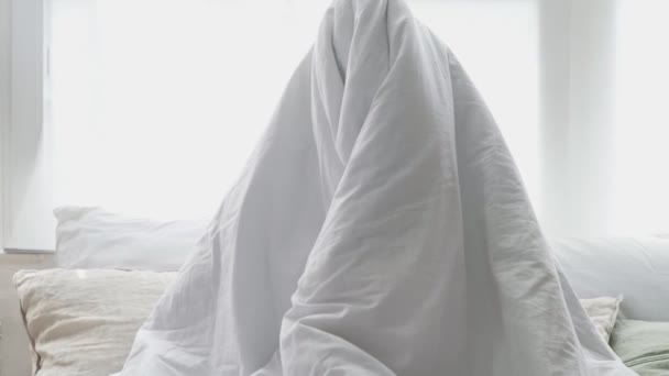 Schöne Frau spielt im Bett versteckt unter einer Decke und genießt den verspielten Morgen zu Hause — Stockvideo
