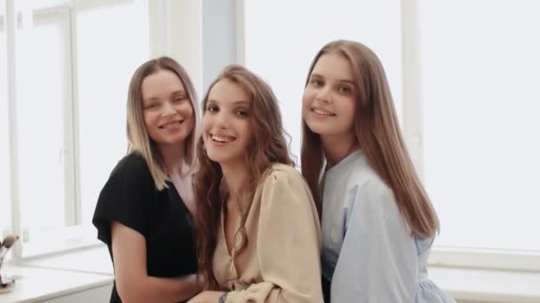 Joven modelo femenina feliz tres mira a la cámara y sonríe — Vídeo de stock