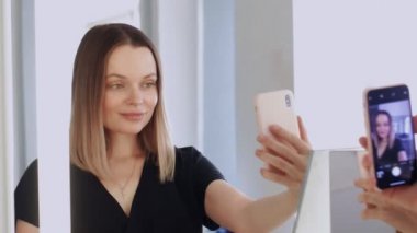 Güzel, doğal, genç bir kadın aynaya bakar. Moda düşkünü bilinçli güzellik blogcusu veya sosyal medya etkileyicisi makyaj yapmaz ve hiçbir filtre fotoğraf çekmez ve telefon kamerasında selfie çekmez.