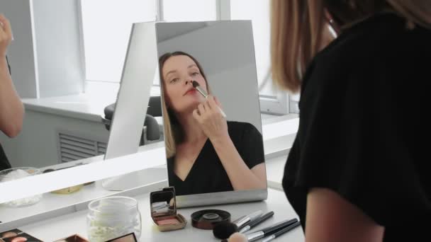 Junge Frau blickt in den Spiegel und trägt Puder auf ihr Gesicht auf — Stockvideo