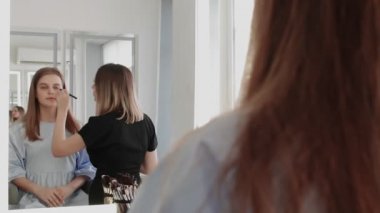 Profesyonel makyöz genç modelin makyajını yapıyor..