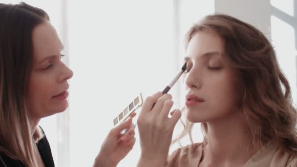 Artista de maquillaje estilista profesional hace modelo de maquillaje de ojos. Modelo de cara con maquillaje de noche vista de cerca — Vídeo de stock