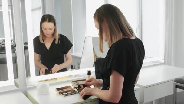 Jonge professionele make-up kunstenaar wacht op klanten en bereidt haar werkruimte — Stockvideo