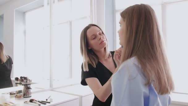 Prozess der professionellen Make-up für schöne und junge Modell sitzt im Studio. — Stockvideo