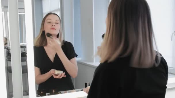 Frau macht Make-up. Junge Frau sorgt mit Make-up-Pinsel für Rouge im Gesicht. — Stockvideo