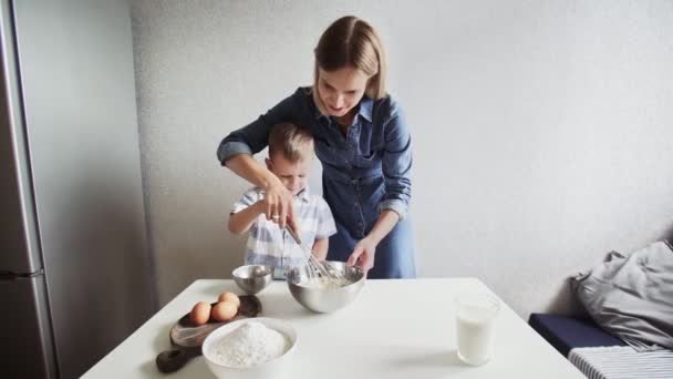 Család a konyhában. Gyönyörű anya a kisfiával tortadombot csinál. — Stock videók