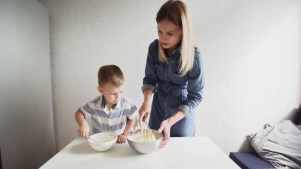 Familjen i ett kök. Vacker mor med liten son gör tårta deg — Stockvideo