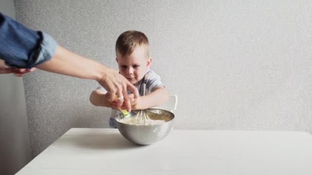 Család a konyhában. Gyönyörű anya a kisfiával tortadarabokat csinál. A fiú citromlevet öntött a tortába. — Stock videók