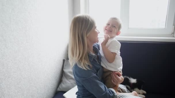 Junge Mutter und ihr Sohn haben Spaß auf der Couch zu Hause — Stockvideo