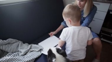 Genç anne ve oğlu evdeki kanepede resim yapıyorlar.