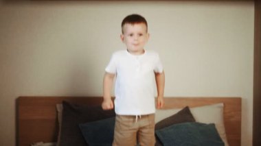 Mutlu küçük çocuğun yatak odasında ebeveyn yatağına atlamasına yakın.