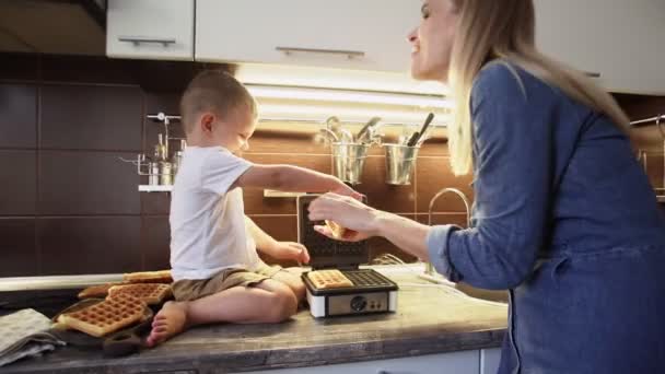 Närbild av unga mor och hennes son gör våfflor i våffla maker hemma kök — Stockvideo