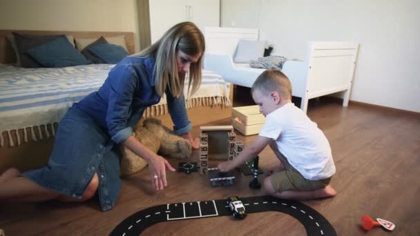 Jeune mère et son fils joue avec les voitures sur le sol — Video