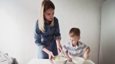 Mutfakta bir aile. Küçük oğlu olan güzel anne kek hamuru yapıyor.