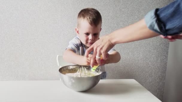 Familjen i ett kök. Vacker mor med liten son gör tårtdeg. Son häller citronsaft i tårta doungh — Stockvideo
