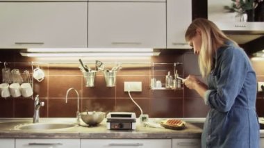 Mutfakta akıllı telefondan yemek fotoğraflayan neşeli bir kadın. Evdeki masada waffle 'ın fotoğrafını çeken tatlı bir kız. Mutfakta cep telefonu kullanan yemek blogcusu