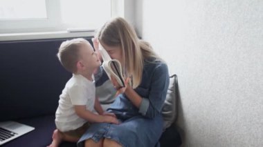 Küçük çocukla evden çalışan genç bir kadın. Oğlu annesinin işini yarıda keserken annesi çalışmaya çalışıyor.