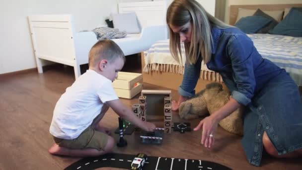 Jeune mère et son fils joue avec les voitures sur le sol — Video