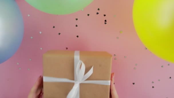 Caixa de presente de aniversário de Natal em mãos de mulher no fundo rosa vista superior — Vídeo de Stock