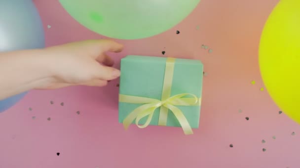 Femme met boîte cadeau d'anniversaire de Noël enveloppé dans du papier vert sur table rose — Video