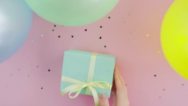 Mujer irreconocible con caja de regalo de cumpleaños de Navidad envuelta en papel verde sobre fondo rosa vista superior — Vídeos de Stock