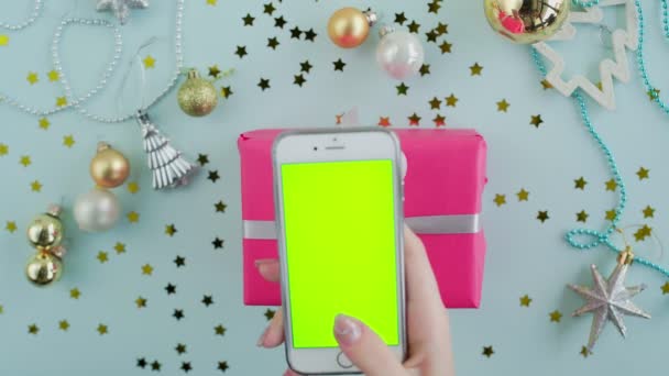 Vista dall'alto della donna utilizza il telefono con schermo verde con scatola regalo rosa sul backgound blu — Video Stock