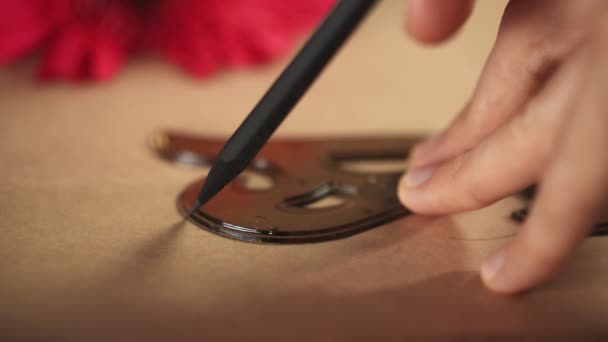 Zbliżenie człowieka używa ołówka i francuskiej krzywej Metric Ruler do malowania na papierze kraft — Wideo stockowe