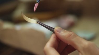 Adam küçük kağıt parçasına pembe boya sürmek için fırça kullanıyor.