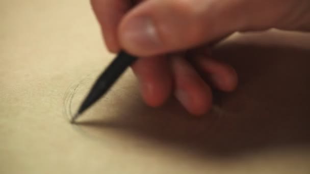 Artista de mano con un lápiz de madera de grafito en papel kraft. Primer plano, macro — Vídeo de stock
