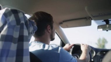 Arabanın içine bak. Genç adam arabayla şehir yolundan geçiyor..